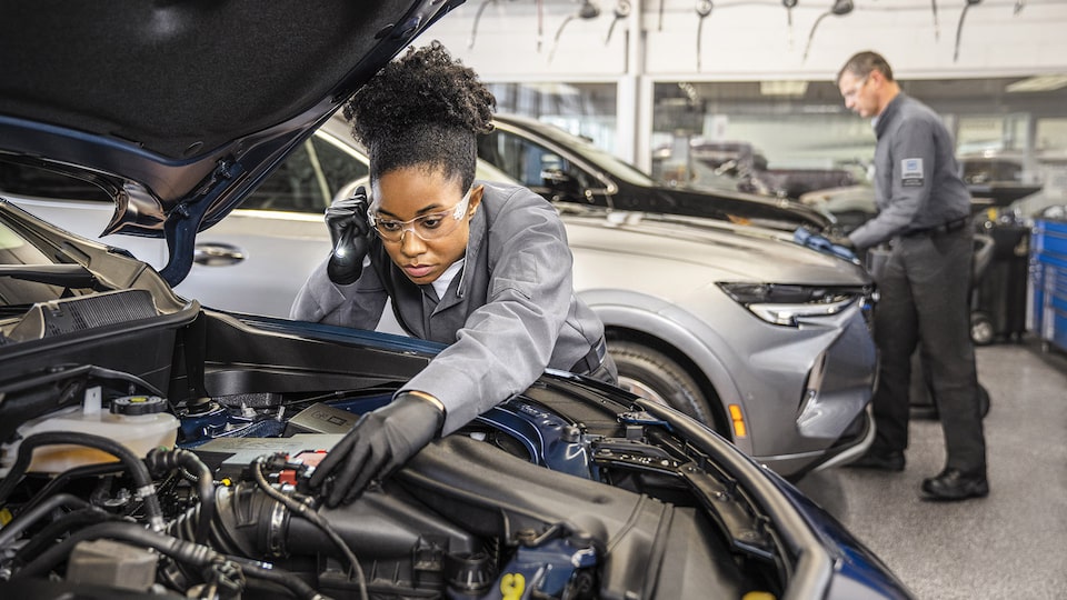 A GM automotive technician performs maintenance on a vehicle.