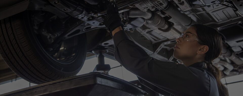 A Certified Service technician performs maintenance on a vehicle