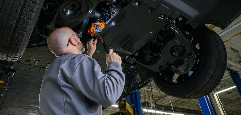 A My Certified Service technician making repairs on the underside of a vehicle.