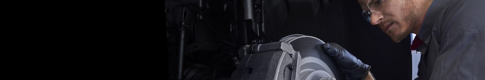 A Certified Service technician inspecting a GM vehicle's brakes and rotors.