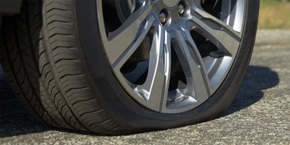 A vehicle at the side of a road with a flat tire requiring roadside assistance.