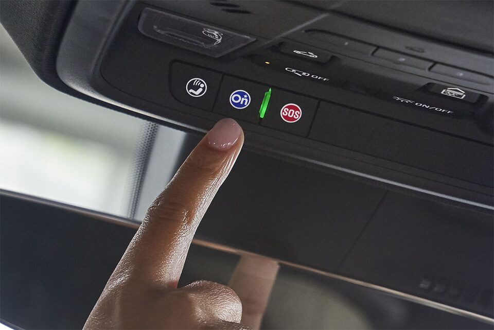 Woman using OnStar button in her vehicle.