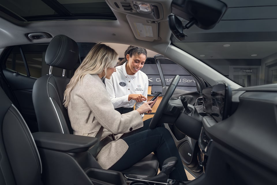 Une personne assise sur le siège du conducteur discutant avec du personnel de vente